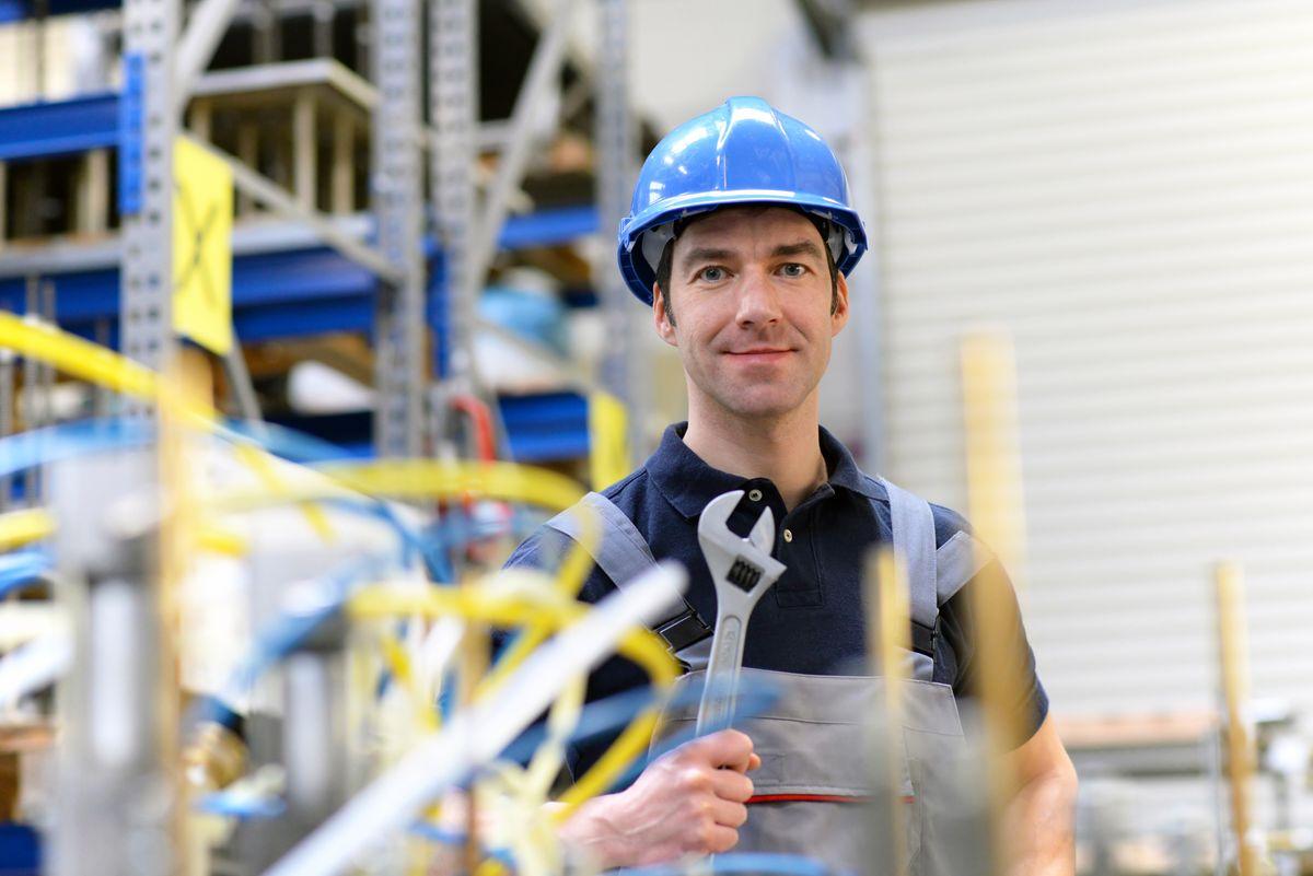 portrait of successful workman in an industrial company, in working clothes at the workplace  - closeup 